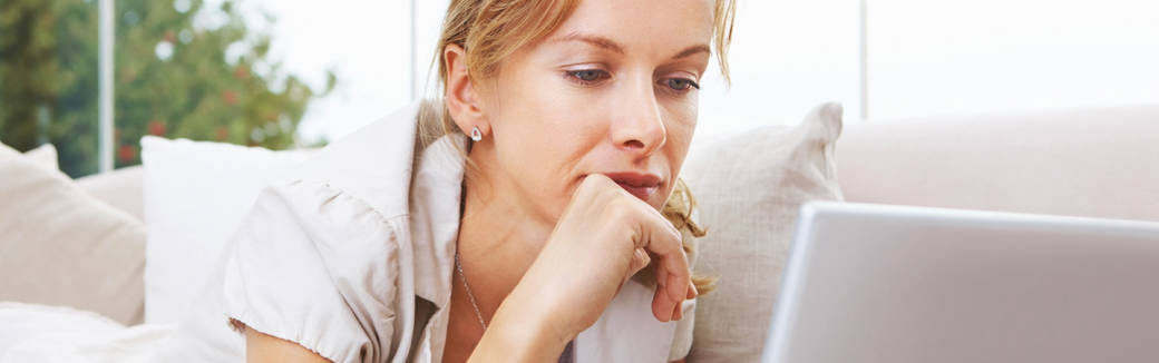 woman with her chin in her hand looking at her computer.